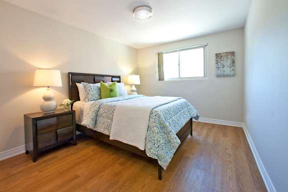 A bedroom with a bed, nightstand, and lamp.