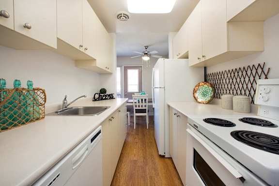 A kitchen with white appliances and wooden floors.