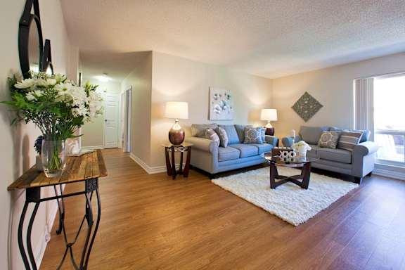 A living room with a couch, a coffee table, and a vase of flowers.