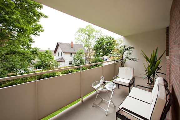 A patio with a white table and chairs overlooks a green yard.