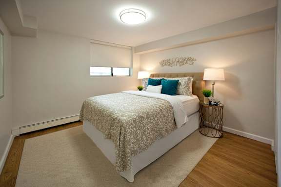 A bedroom with a bed, a lamp, and a rug.