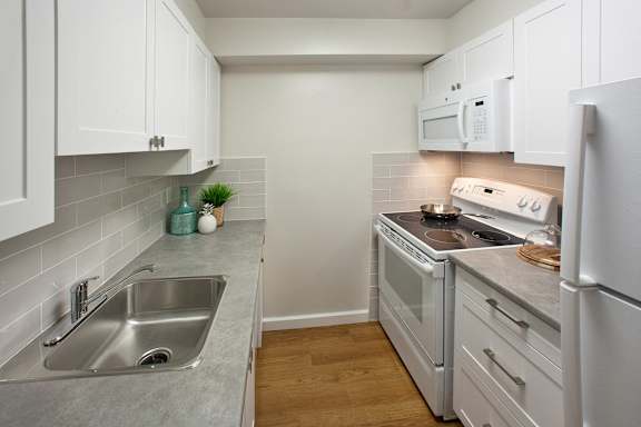 A kitchen with white cabinets and a grey counter top.