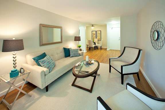 A living room with a white couch, a coffee table, and a mirror on the wall.