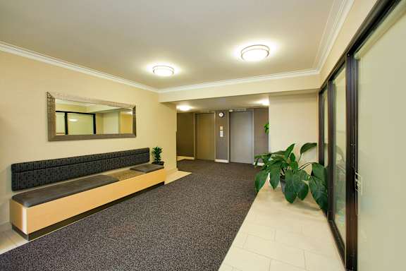 A hallway with a bench, mirror, and two doors.