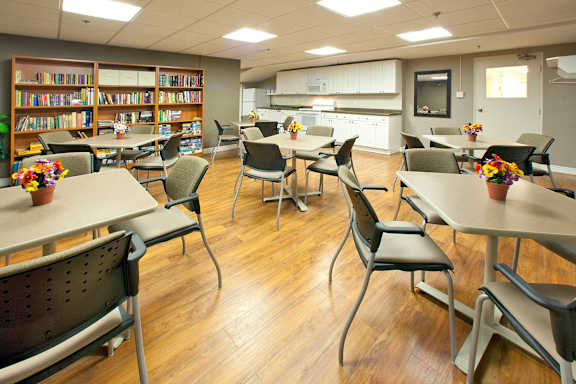 A room with tables and chairs and a bookshelf.