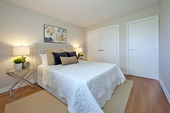 A bedroom with a white bed and a painting above it.