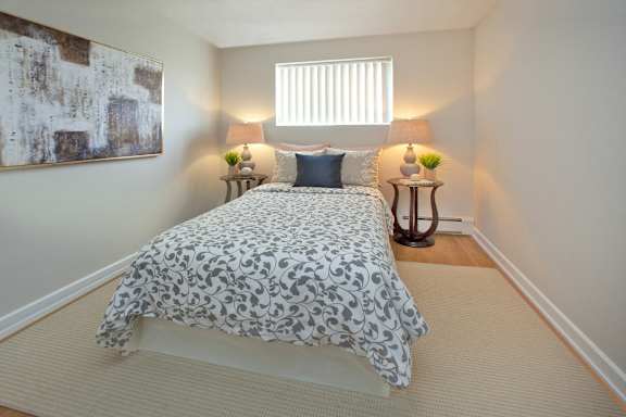 A bedroom with a bed, two lamps, and a painting on the wall.