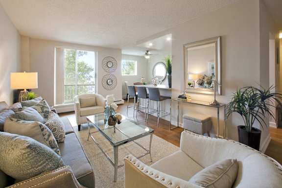 A living room with a glass coffee table and white couches.