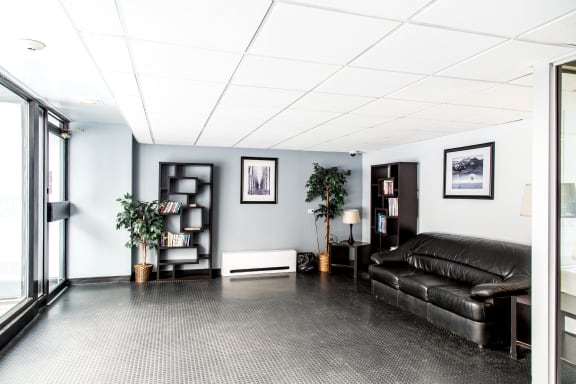 a living room with a black leather couch and a window
