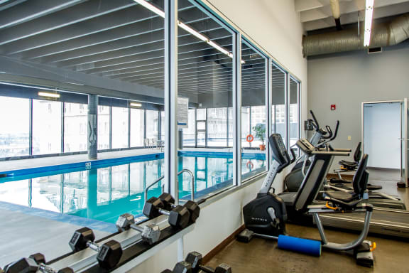 a gym with cardio equipment and a window view of a swimming pool