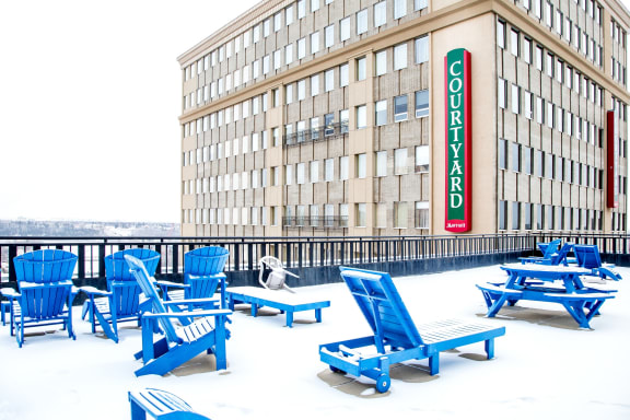 a group of blue lounge chairs in the snow in front of a building