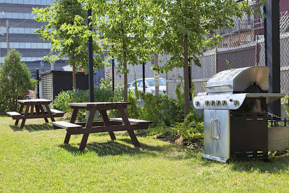 A picnic table and a grill are set up in a grassy area.