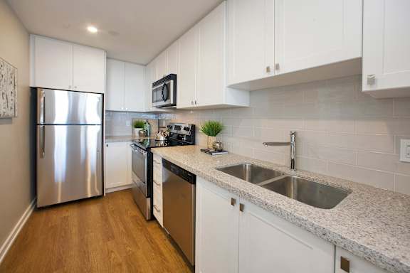 A kitchen with white cabinets and a stainless steel refrigerator.