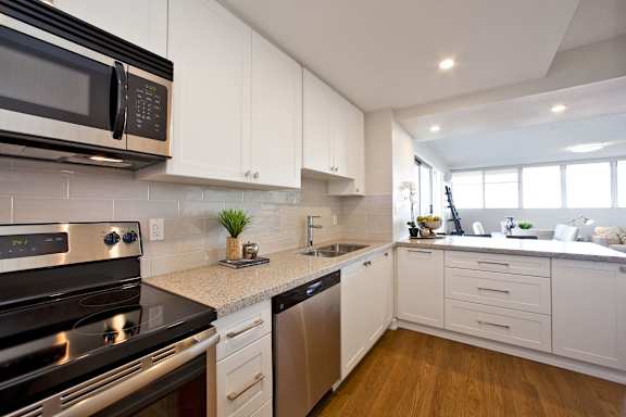 A modern kitchen with white cabinets and stainless steel appliances.