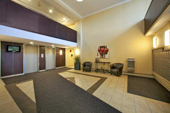 A hallway with a TV on the wall and a few chairs and tables.