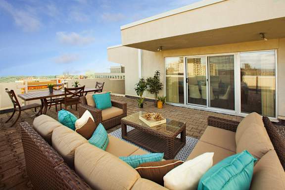 A patio with a couch, chairs, and a table with a pineapple on it.