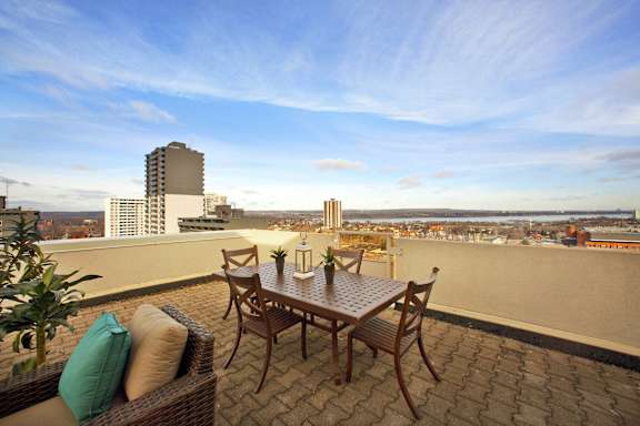 A patio with a table and chairs overlooking a cityscape.
