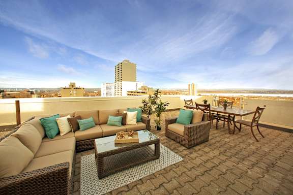 A patio with a couch, chairs, and a coffee table with a view of the city.