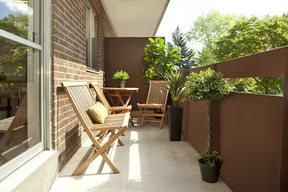 a patio with wooden chairs and a table on a balcony