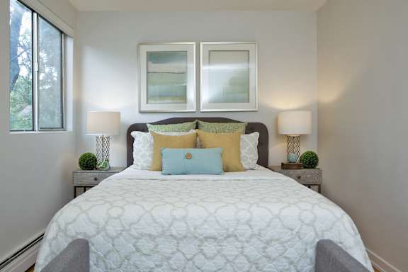 a bedroom with a white bed and two windows