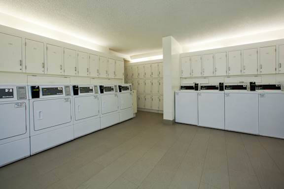 an empty laundry room with rows of washers and dryers