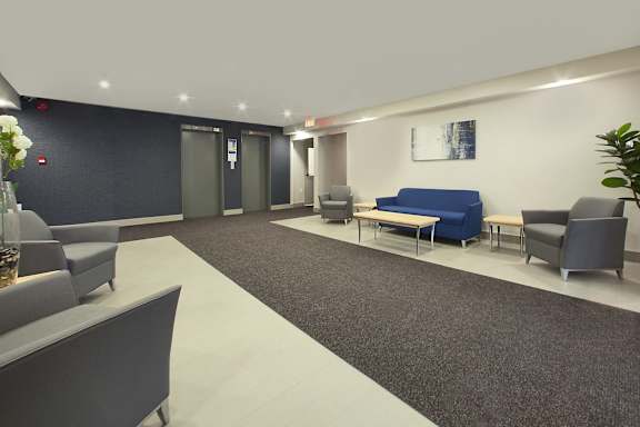 a lobby with blue couches and chairs and a rug