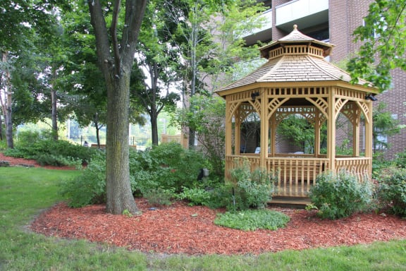 a gazebo in a garden next to a tree