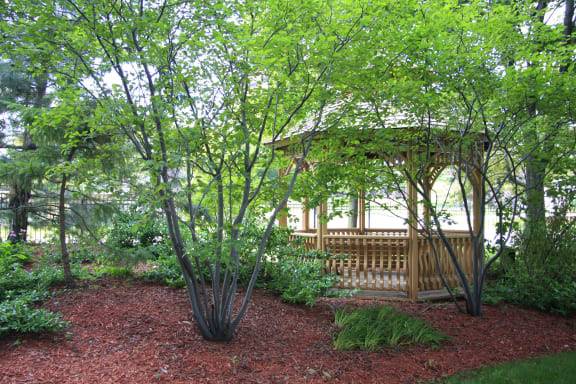 a gazebo in the middle of a garden with trees