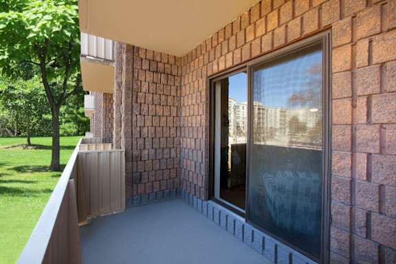 a balcony with a brick wall and a glass door