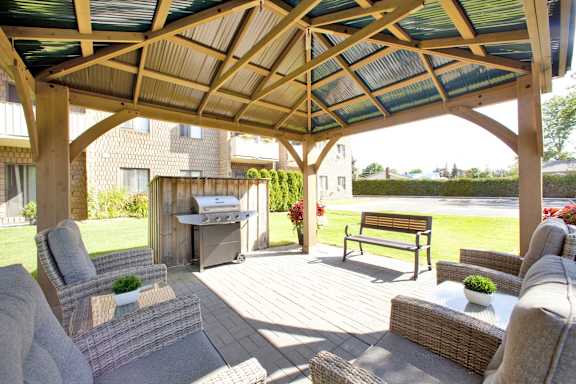 a covered patio with furniture and a grill