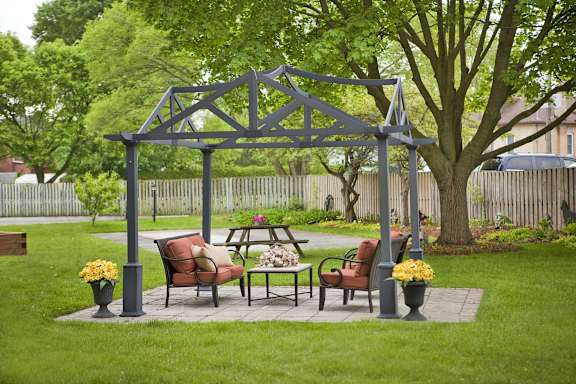 a patio with a gazebo and a table and chairs in a backyard