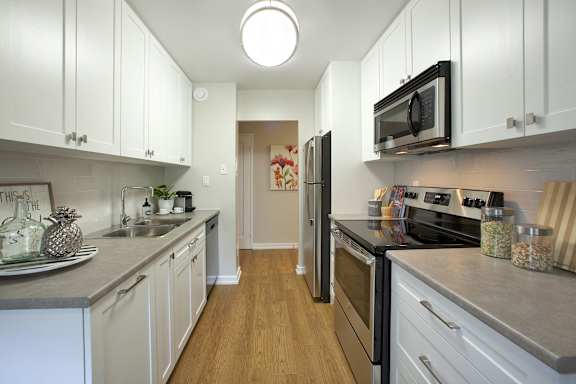 a kitchen with white cabinets and stainless steel appliances and a black refrigerator