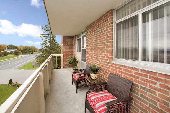 a balcony with two chairs and a table and a brick wall