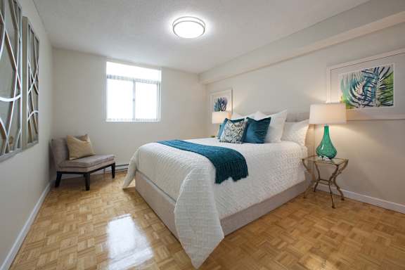 a bedroom with a bed and a chair and a window
