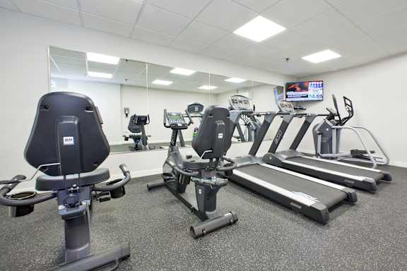a gym with various exercise equipment and a tv