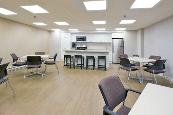 a multipurpose room with tables and chairs and a kitchen