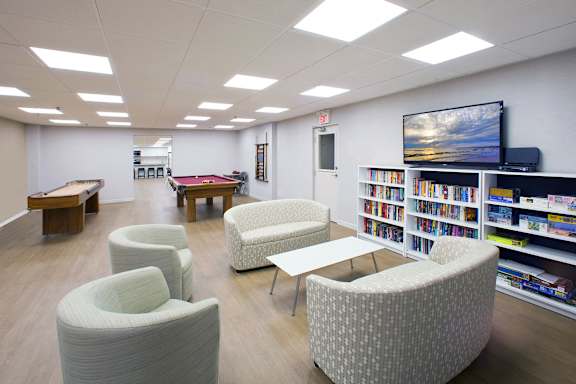 a library with couches tables and chairs and a pool table