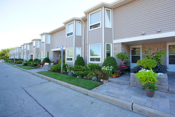 a street in front of an apartment building with potted plants