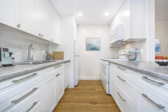 a kitchen with white cabinets and stainless steel appliances and a sink