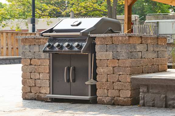 a barbecue grill in a stone wall in a backyard