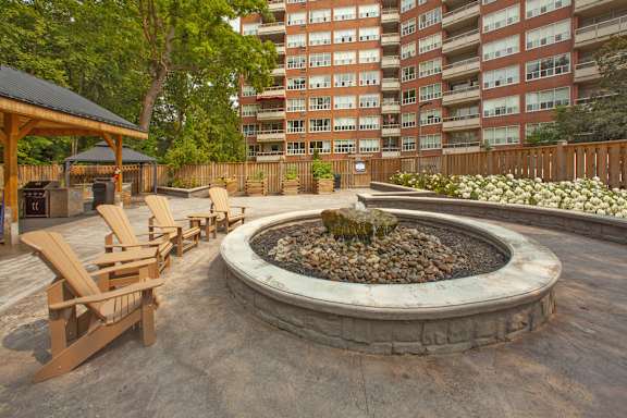 a fire pit with wooden chairs in front of an apartment building