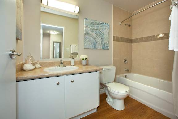 A white toilet sits in a bathroom with a white sink and a white bathtub.