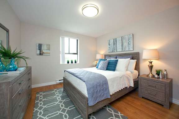 A bedroom with a bed, nightstand, and a rug.