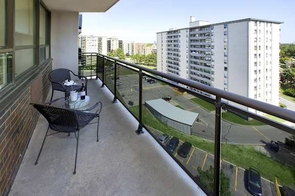 a balcony with a table and chairs and a view of a parking lot