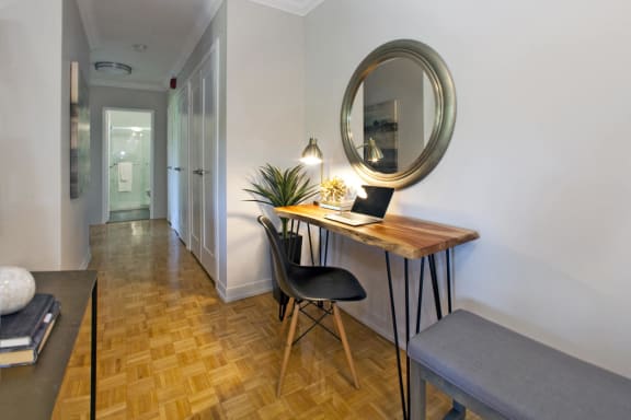 a room with a desk with a laptop on it and a mirror
