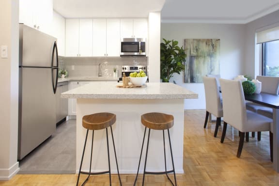 a kitchen and dining area with white cabinets and a marble counter top