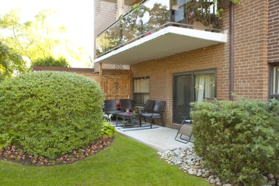 a patio with chairs in front of a brick house