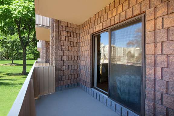 a balcony with a brick wall and a glass door