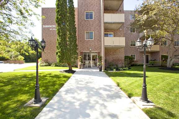 a sidewalk in front of an apartment building with lawns and trees