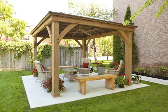 a patio with a wooden pavilion with a table and chairs